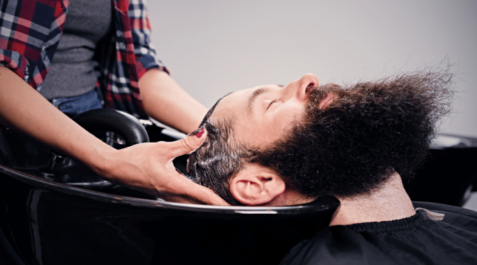Man with black hait and beard having hair washed at salon